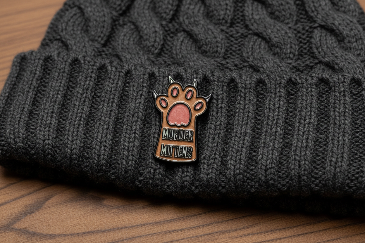 Small enamel pin with a paw design and text on a beanie hat background