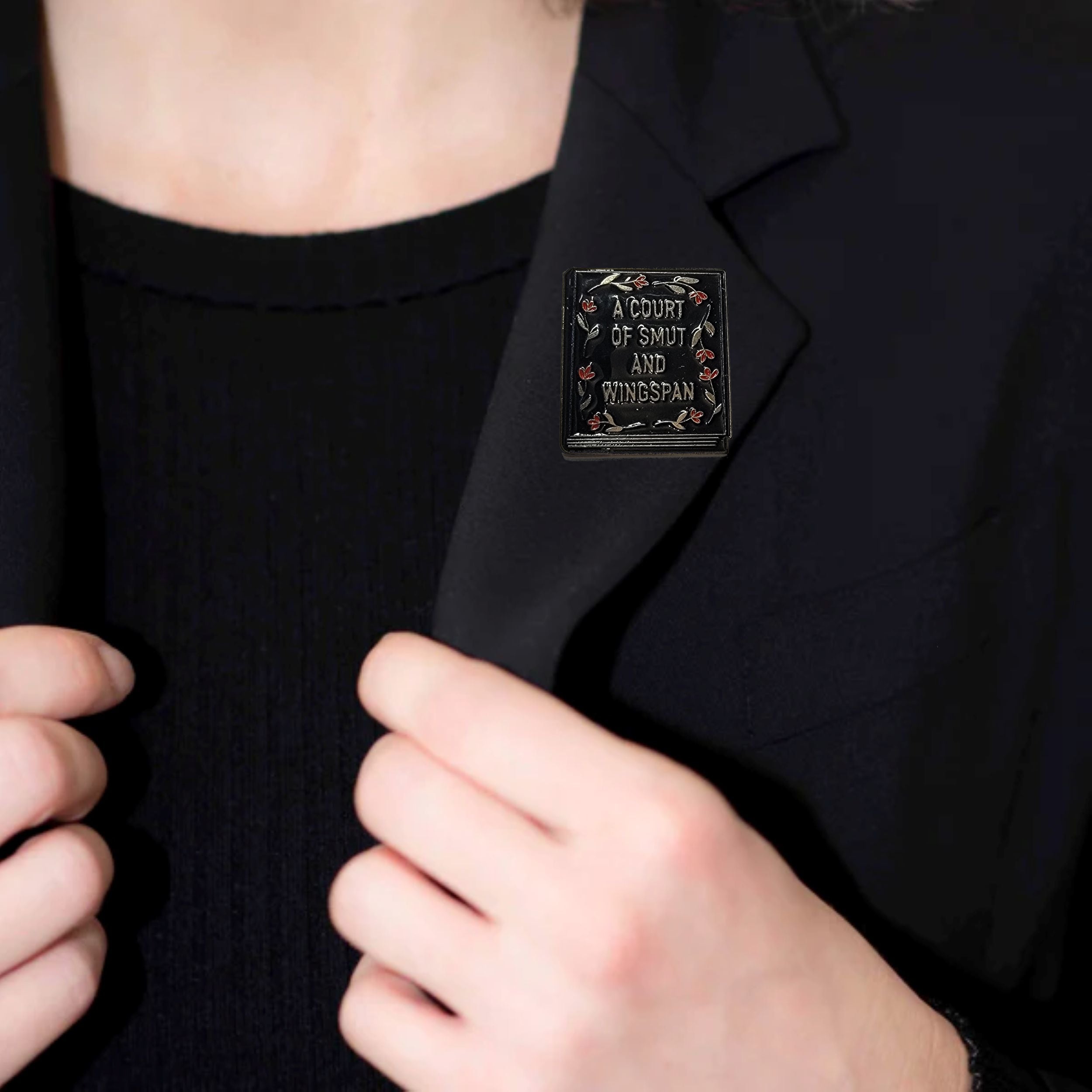 Person wearing a black blazer with a unique design on the chest pocket.