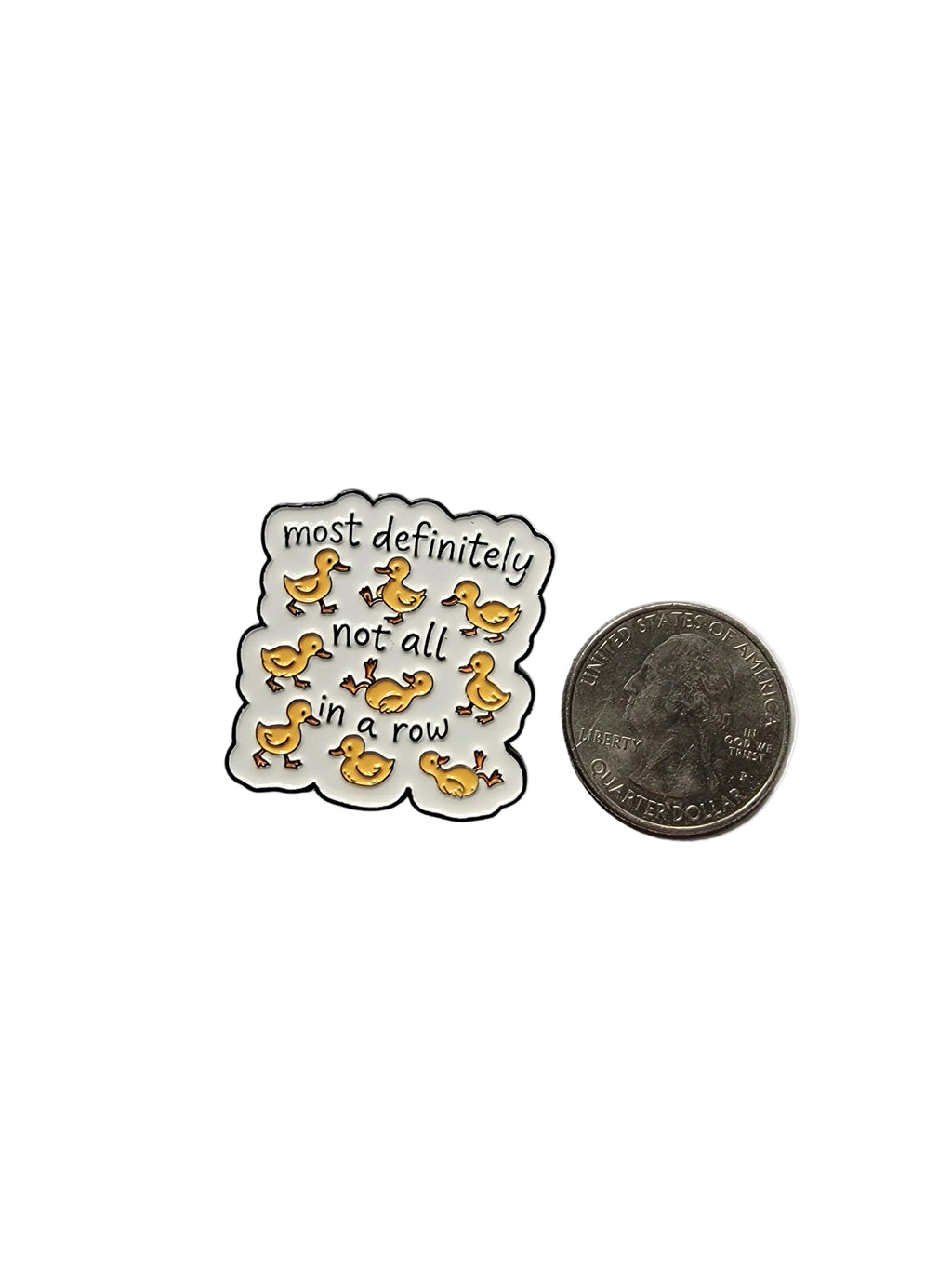 Pin with text and duck illustrations next to a quarter on a gray background
