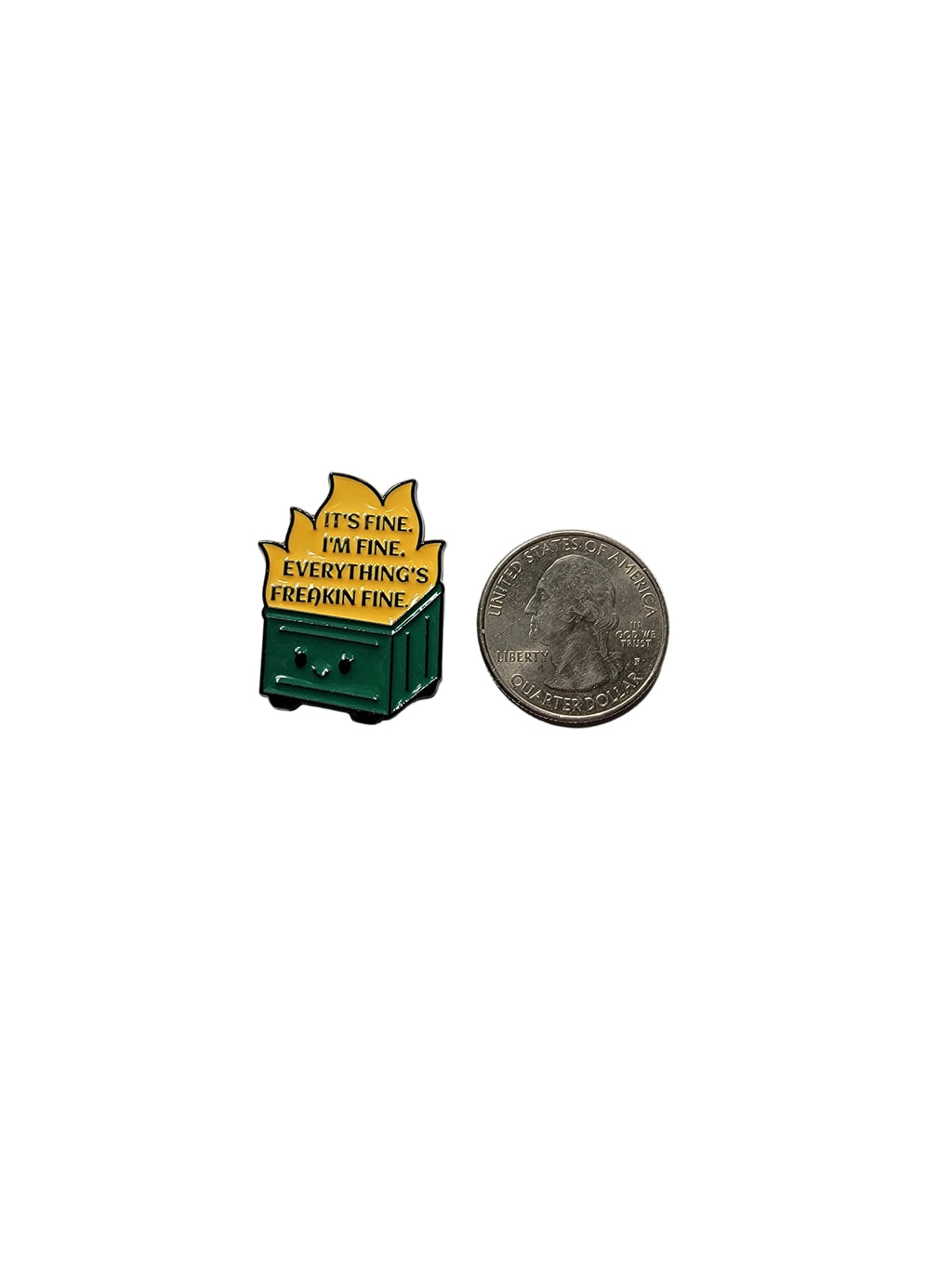 Small green and yellow pin with text on a gray surface next to a coin for scale.