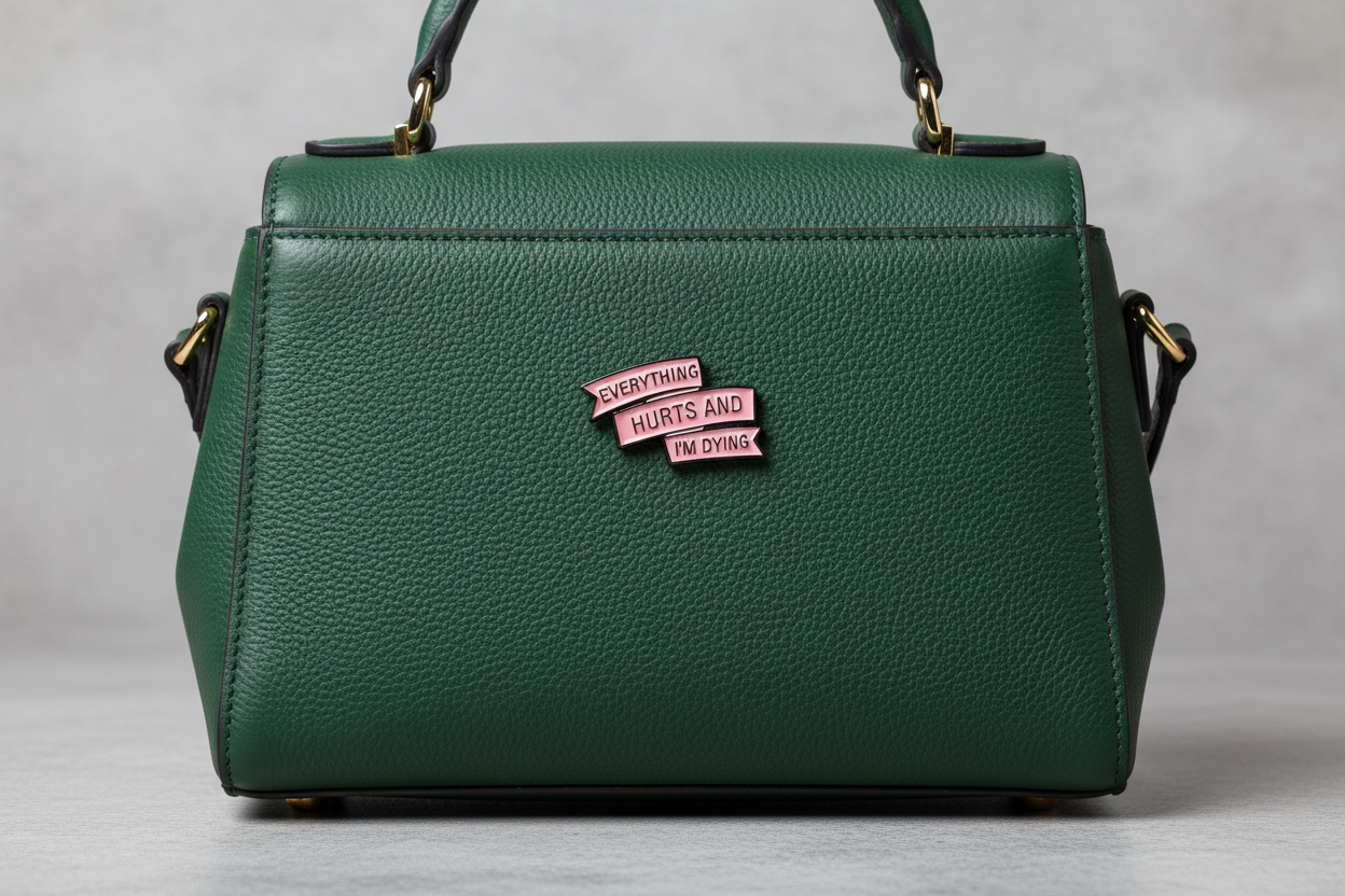 Metallic pink enamel pin with text on a green background