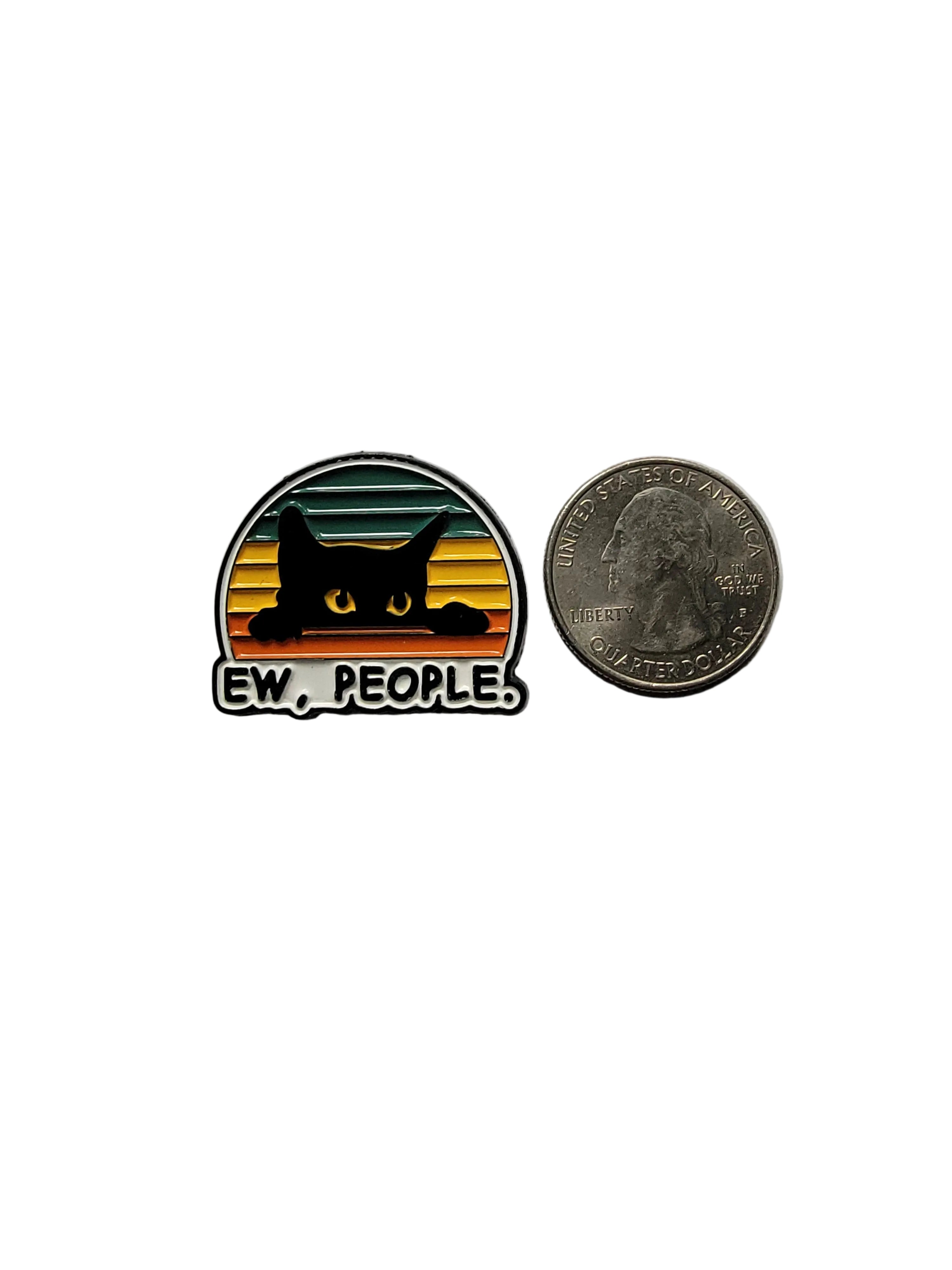 Pin with black cat design and 'EW. PEOPLE.' text on a gray background, next to a quarter for scale.