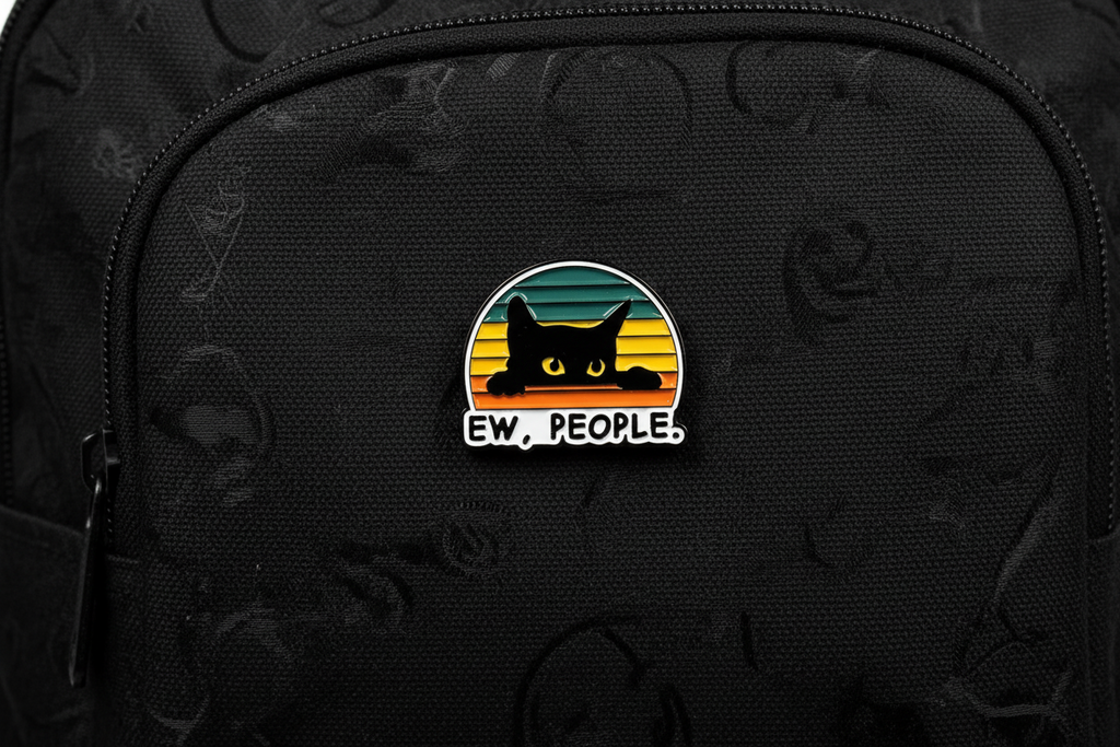 Pin with a black cat design and 'EW. PEOPLE.' text on a black bookbag background