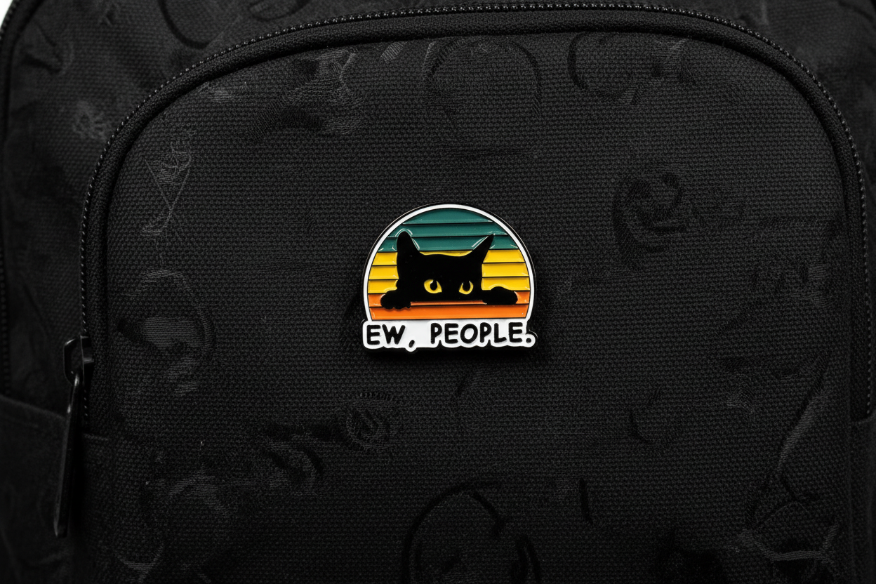 Pin with a black cat design and 'EW. PEOPLE.' text on a black bookbag background
