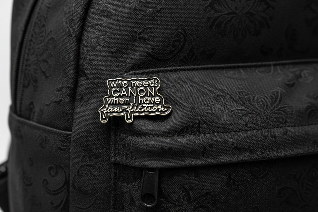 a black enamel pin with gold text on a black bookbag background