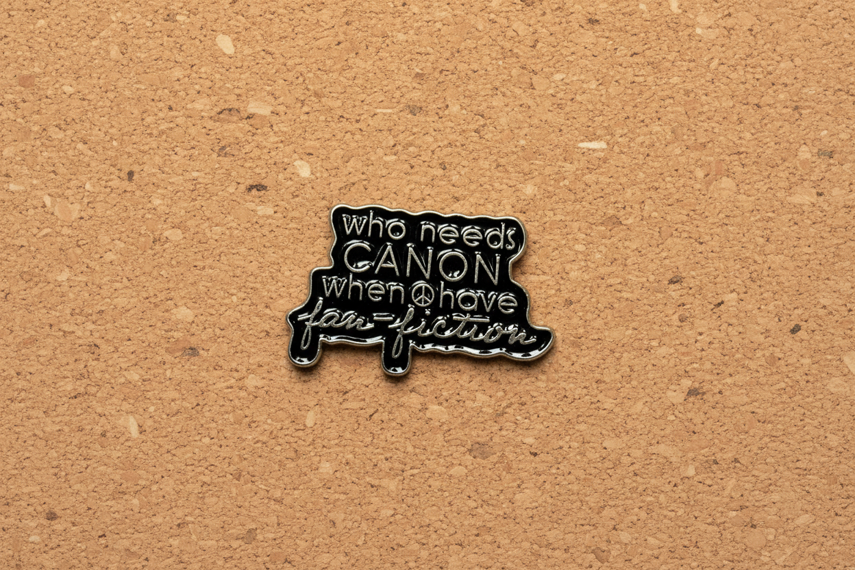 a black enamel pin with gold text on a cork background