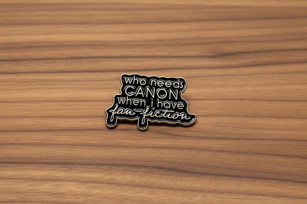 a black enamel pin with gold text on a wood background