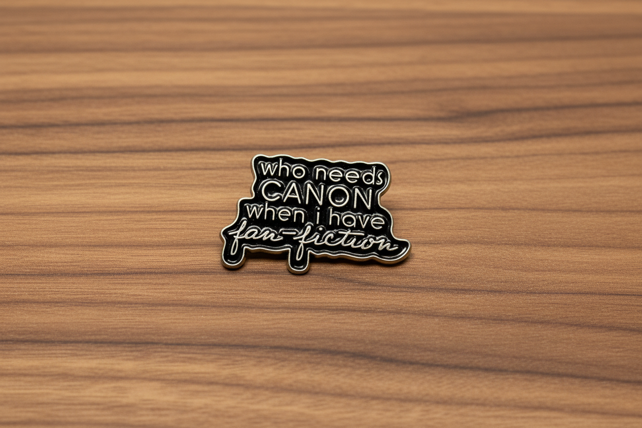 a black enamel pin with gold text on a wood background