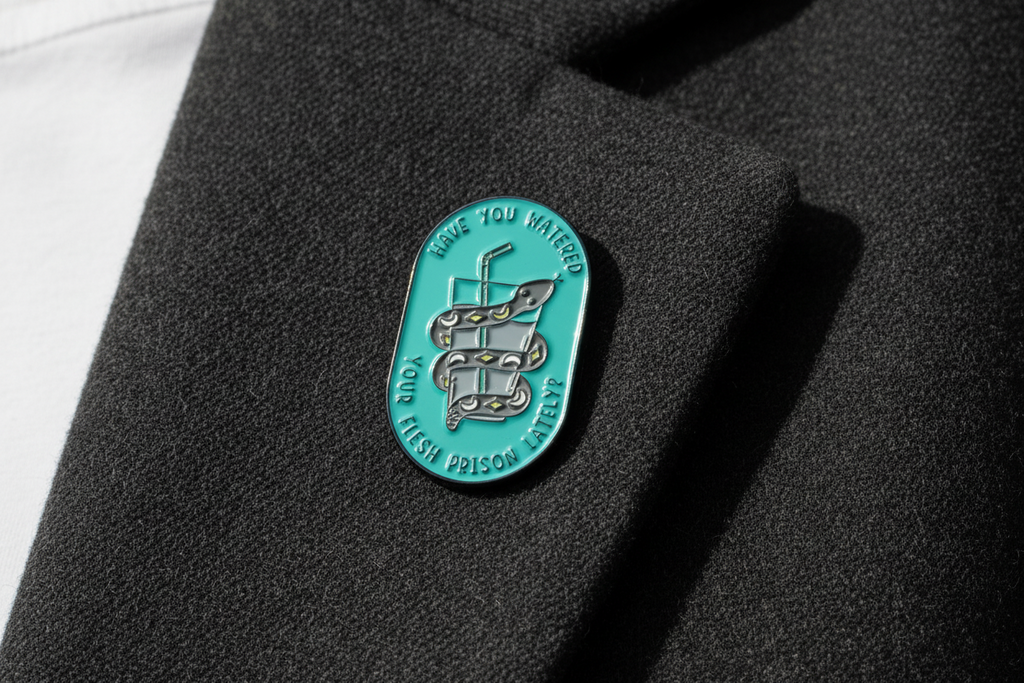 a teal pin with a snake and water on a lapel background