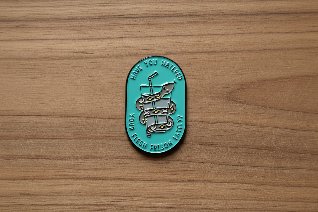 a teal pin with a snake and water on a wood background