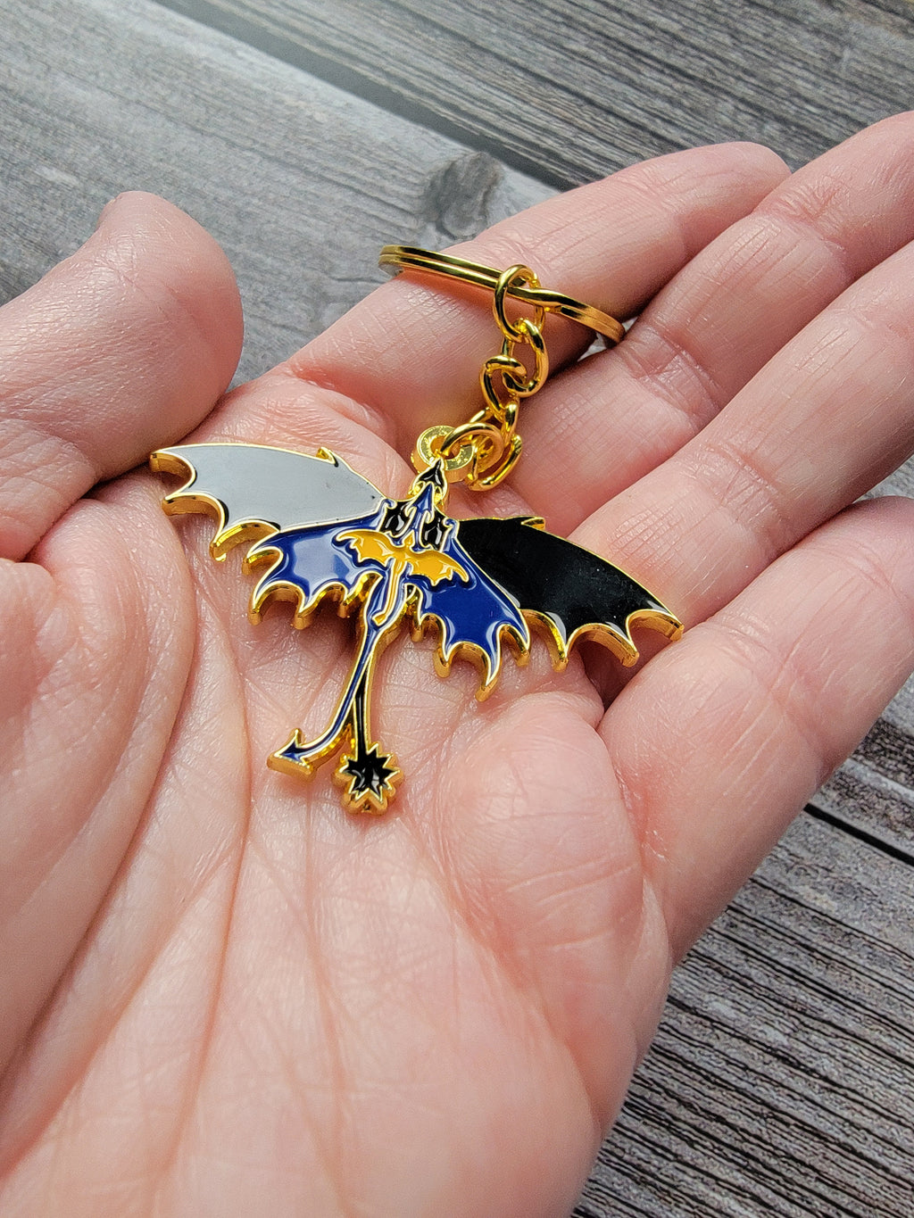 Keychain with a blue and gold design held in a hand on a wooden surface