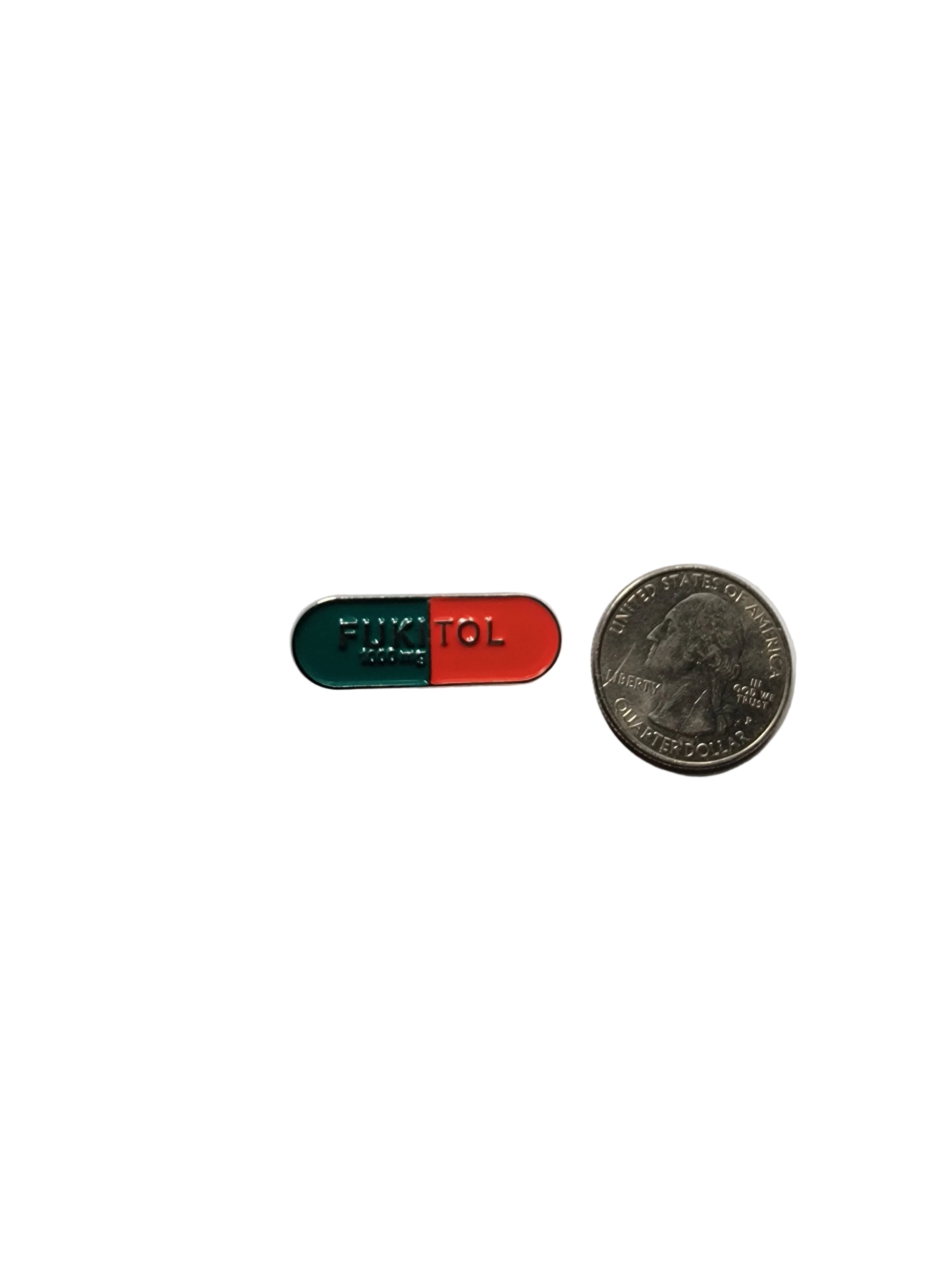red and blue pin on a white background next to an American quarrter