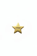 Gold star-shaped object with 'i tried ' engraved on a white background