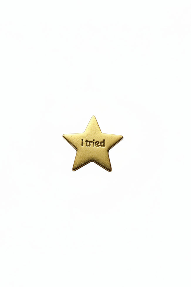 Gold star-shaped object with 'i tried ' engraved on a white background