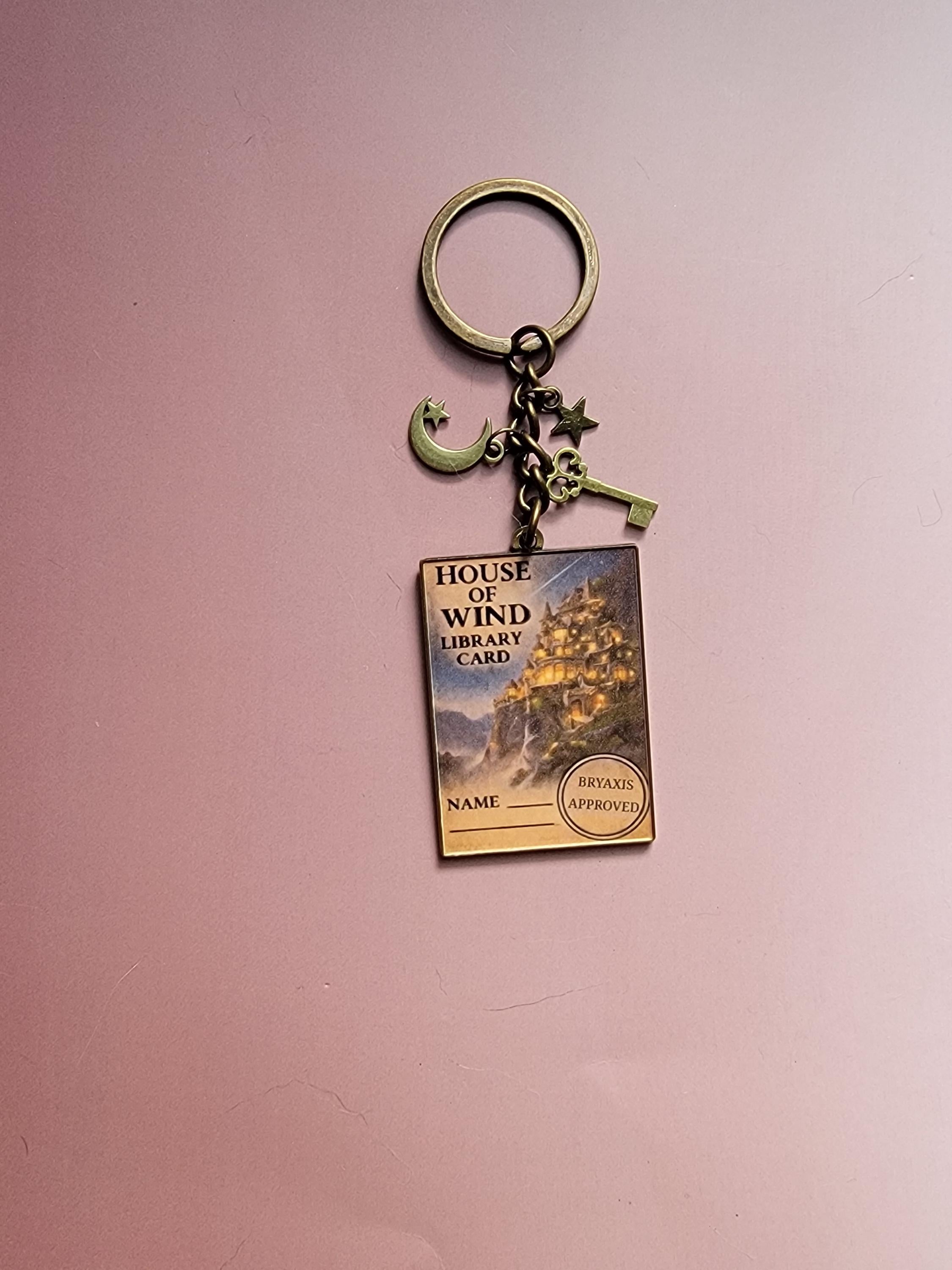 Keychain with book-themed design on a pink background