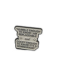white enamel pin with black text on a white background
