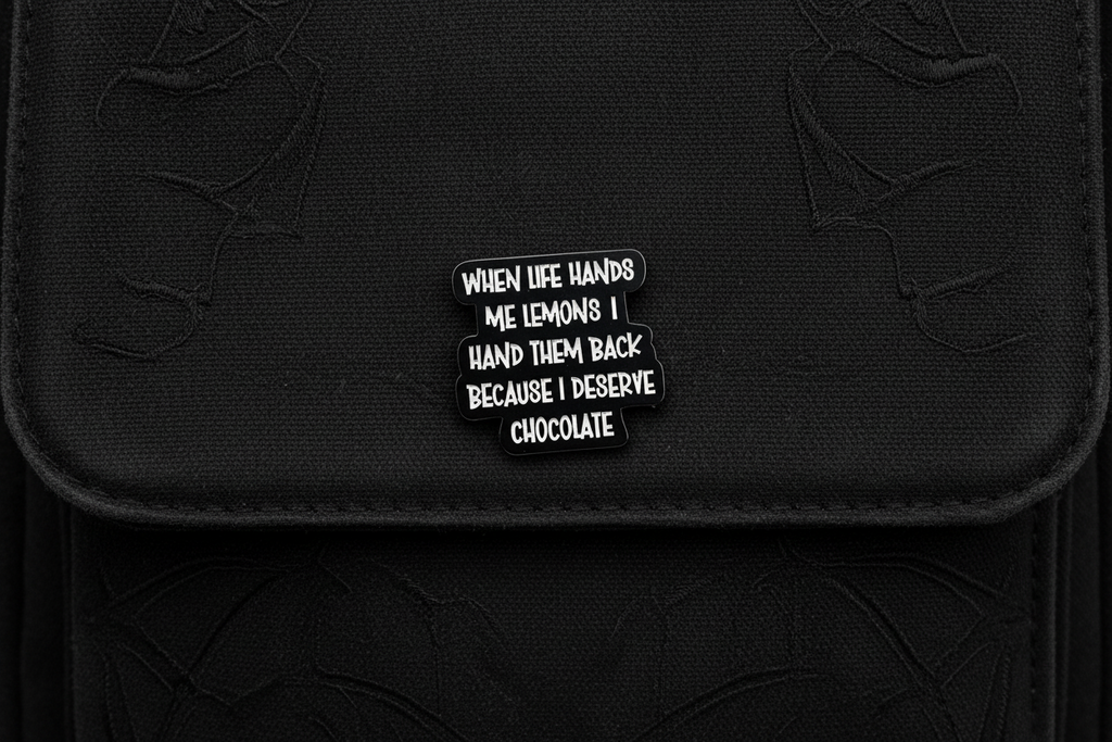 a black pin with white text with a funny quote on a black bookbag background