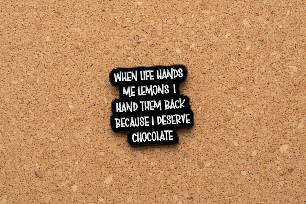 a black pin with white text with a funny quote on a cork background