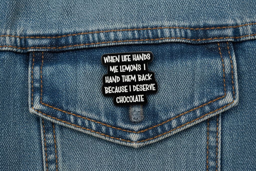 a black pin with white text with a funny quote on a denim background