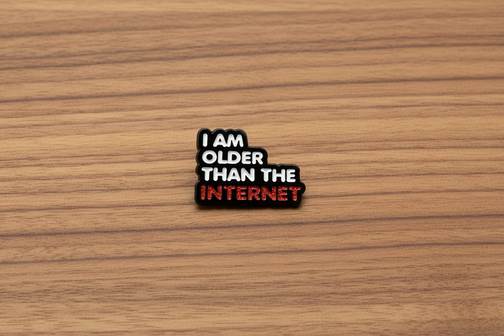 Enamel pin with 'I am older than the internet' text on a wood background