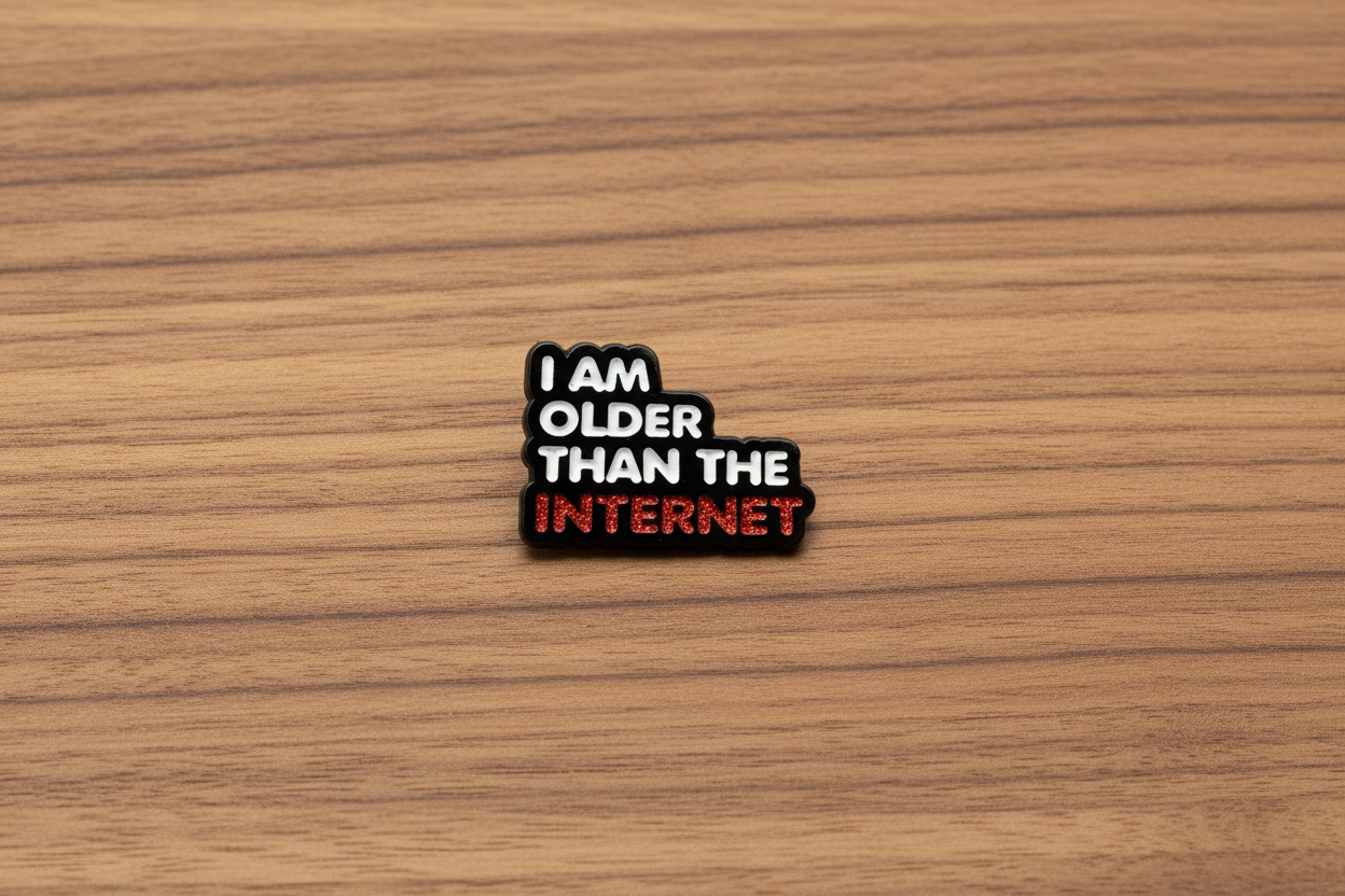 Enamel pin with 'I am older than the internet' text on a wood background