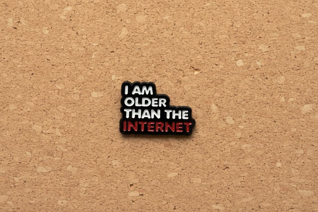 Enamel pin with 'I am older than the internet' text on a cork background