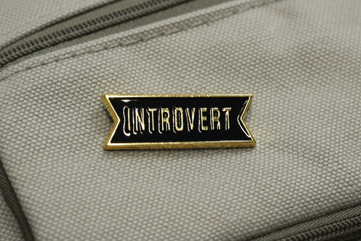 Pin with 'Introvert' text on a gray backpack