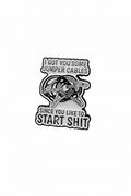 white enamel pin with black text and jumper cables on it on a white background