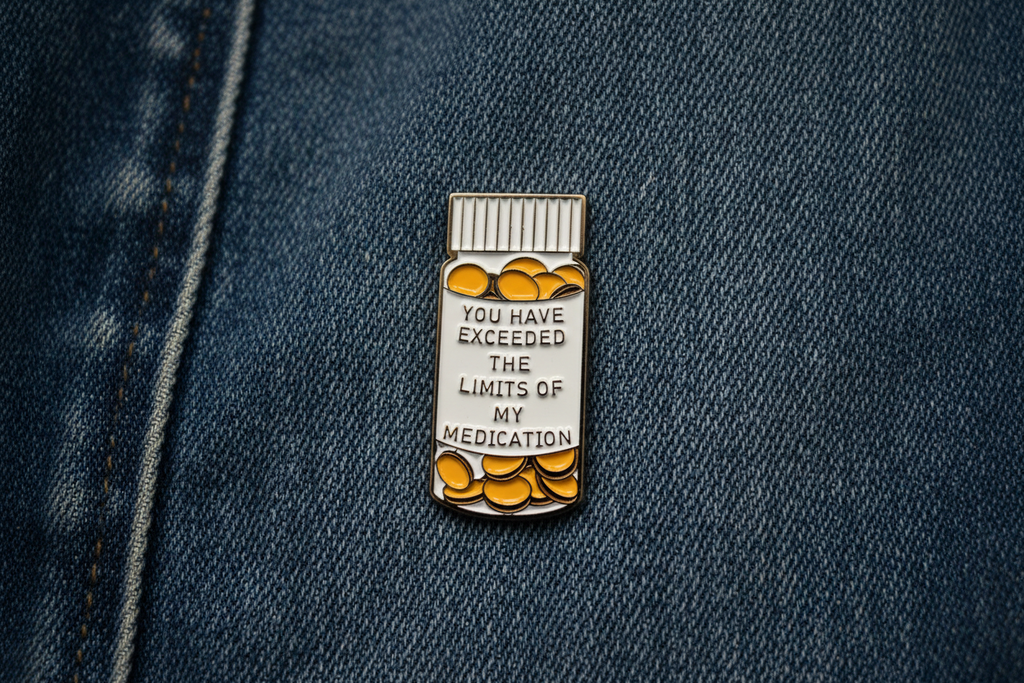medicine bottle pin with text on a denim background