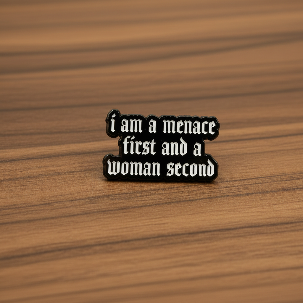 I am a menace first enamel pin on wood background chaotic enamel pin with black and white text detail