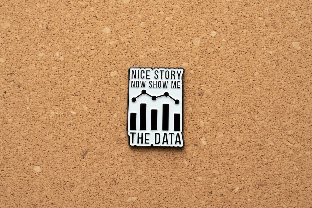 Metallic badge with text 'Nice story, now show me the data' on a cork background