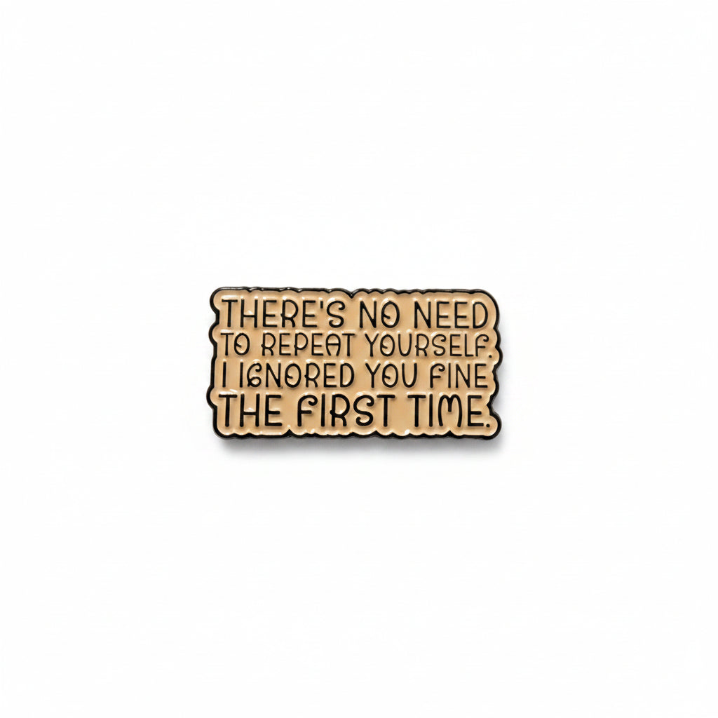a beige enamel pin with black text on a white background