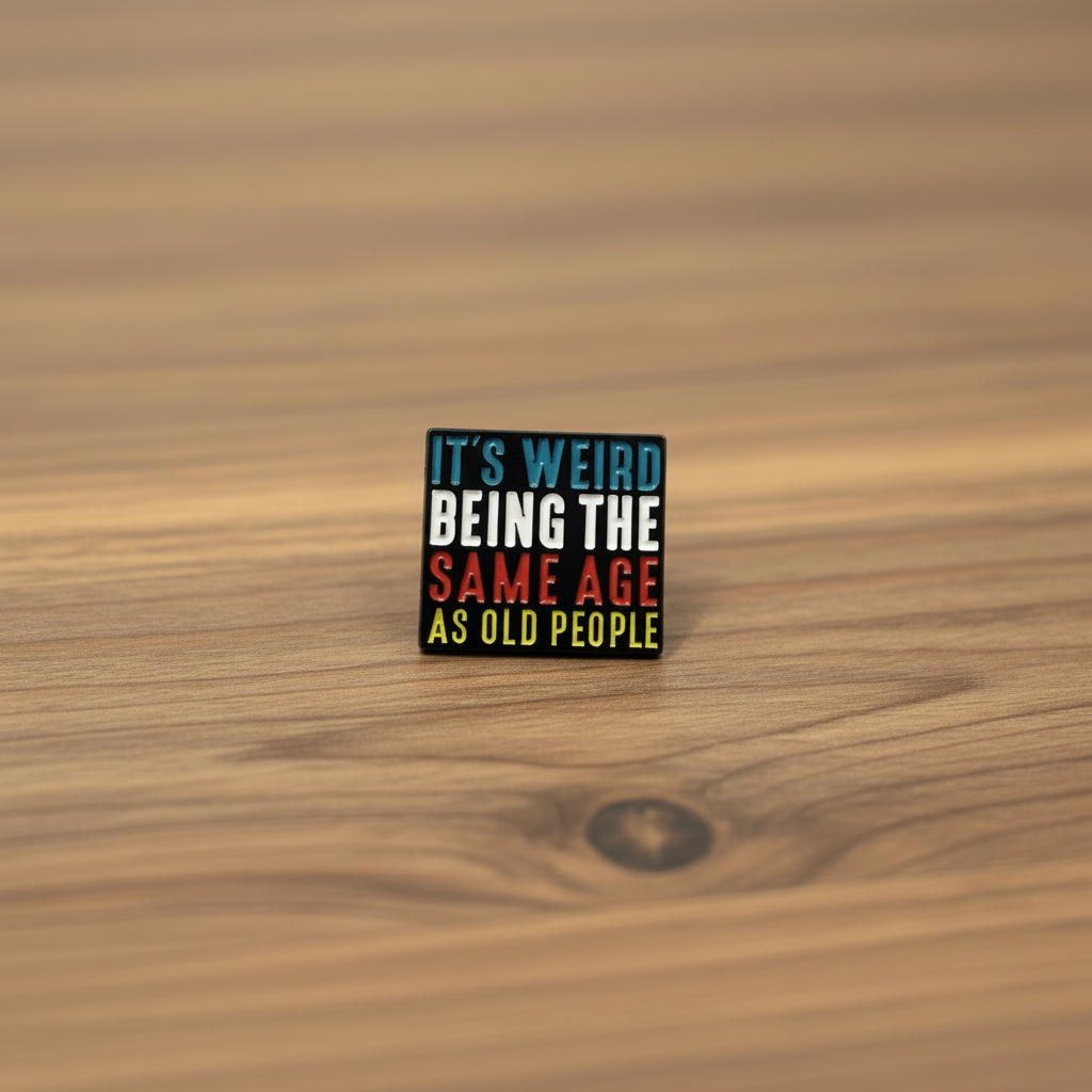 It's weird being the same age as old people enamel pin on wood background sarcastic enamel pin with multicolored text detail