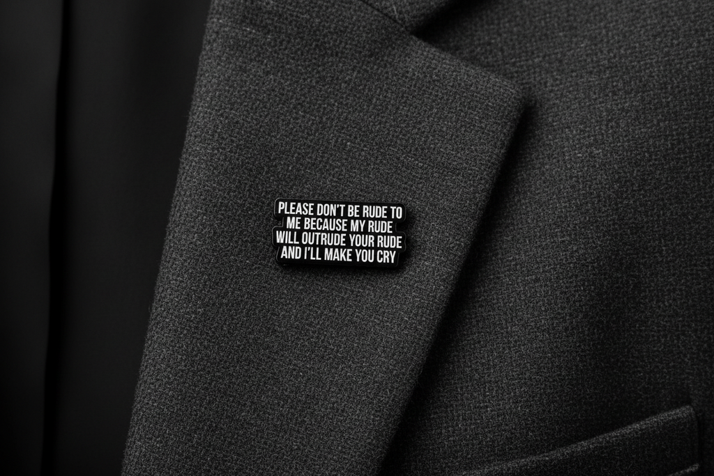 Black metal badge with white text on a gray fabric background