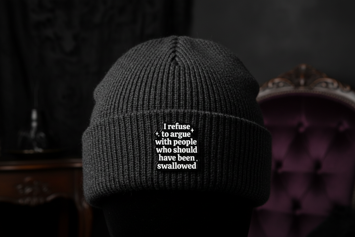Black and white text pin on a black beanie hat background