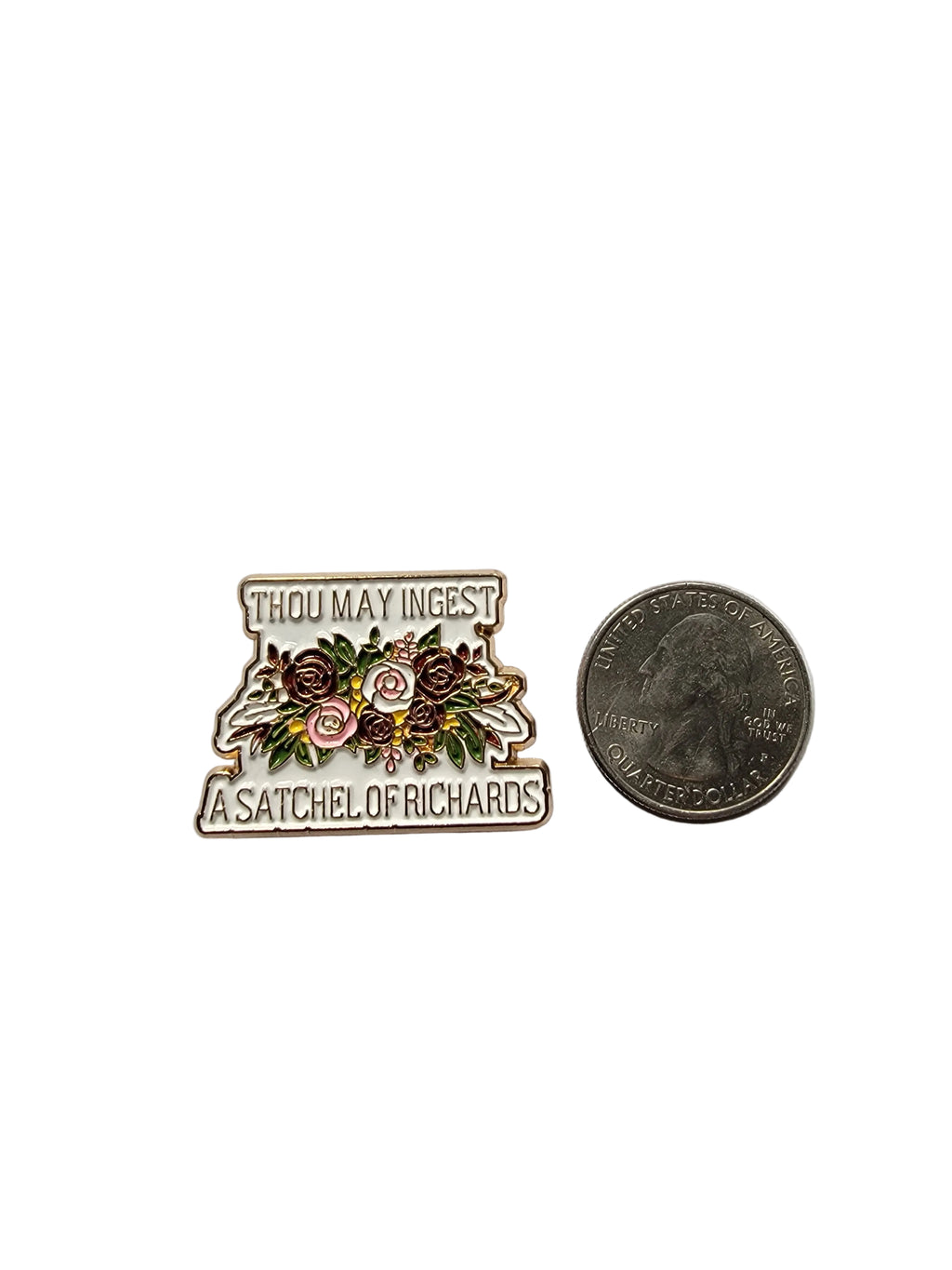 Small decorative pin with floral design and text, compared in size to a quarter on a gray background