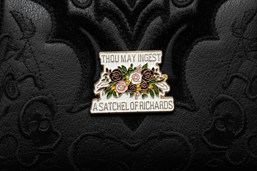 a enamel pin with text and a floral design on a black fabric background