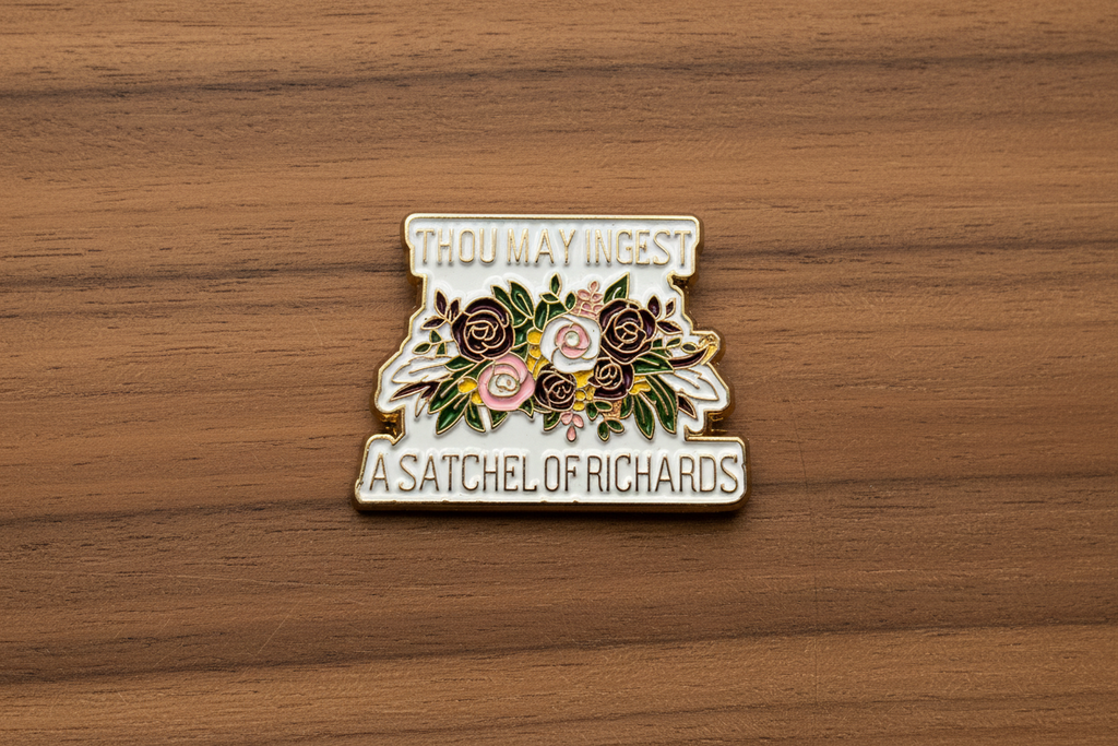 a enamel pin with text and a floral design on a wood background
