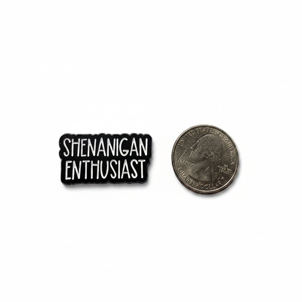 Shenanigan Enthusiast enamel pin shown next to quarter for size reference funny enamel pin dims 1 1/4 in W x 1/2 in H