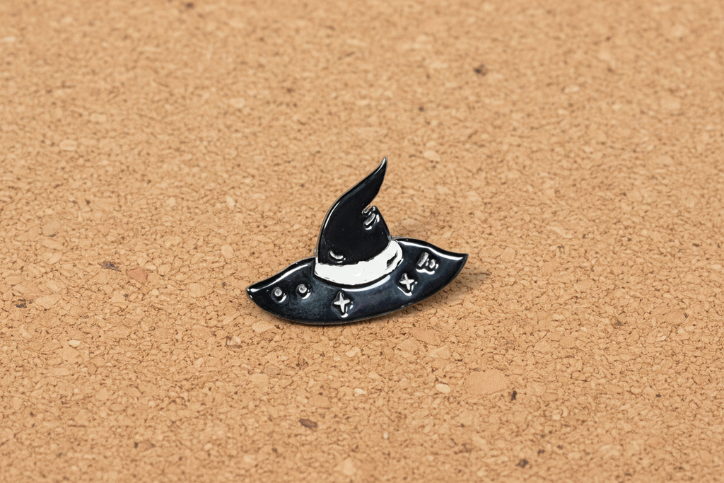 silver witch hat enamel pin displayed on cork board goth enamel pin for collectors and display