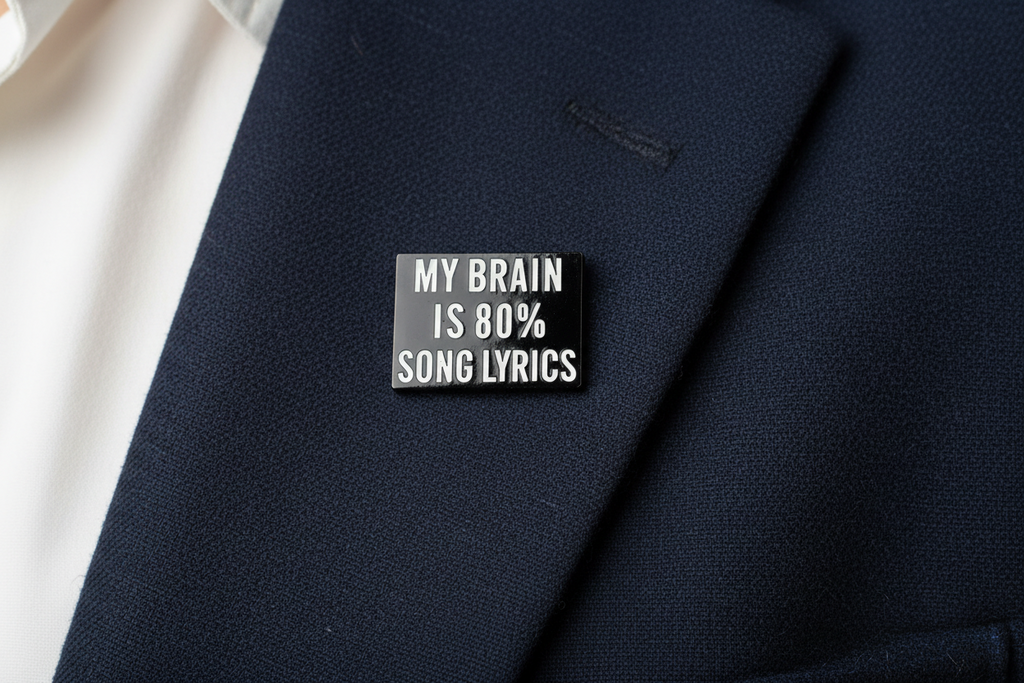 Small black rectangular pin with white text on a navy fabric background