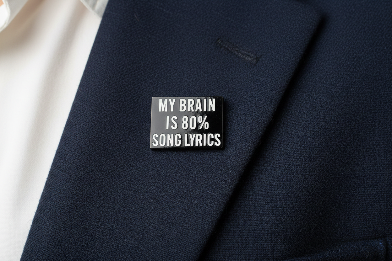 Small black rectangular pin with white text on a navy fabric background