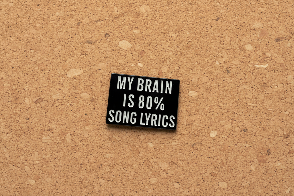Small black rectangular pin with white text on a cork background