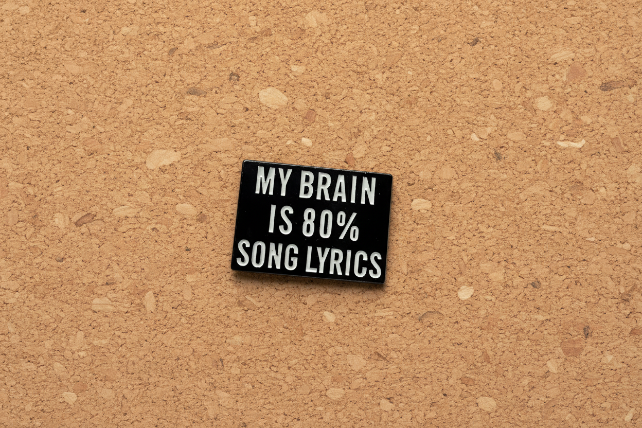 Small black rectangular pin with white text on a cork background