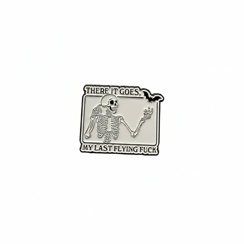 White enamel pin with skeleton and black text on a white background. 