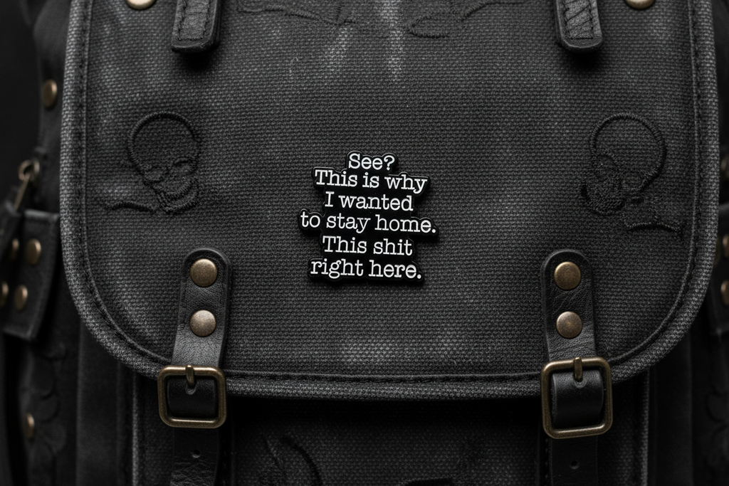 A black sarcastic pin with white text on a black bookbag background