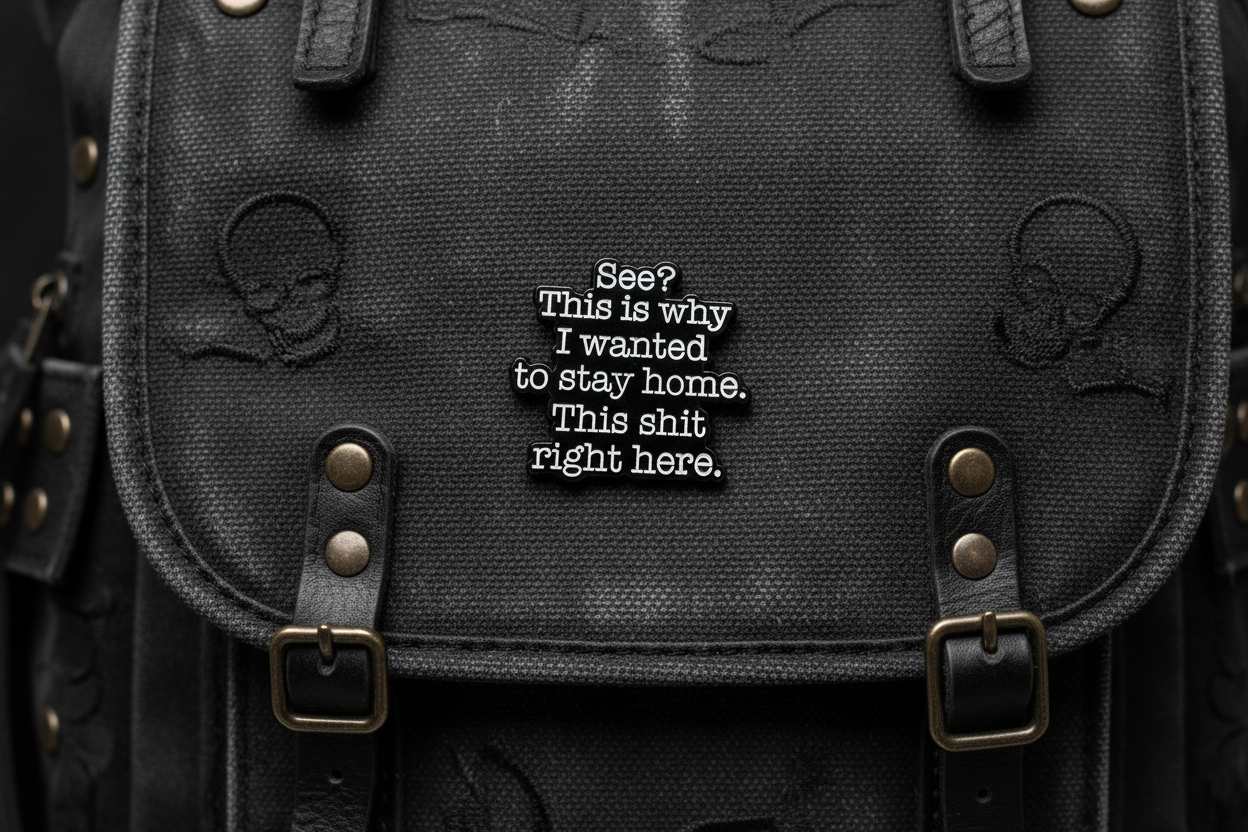 A black sarcastic pin with white text on a black bookbag background