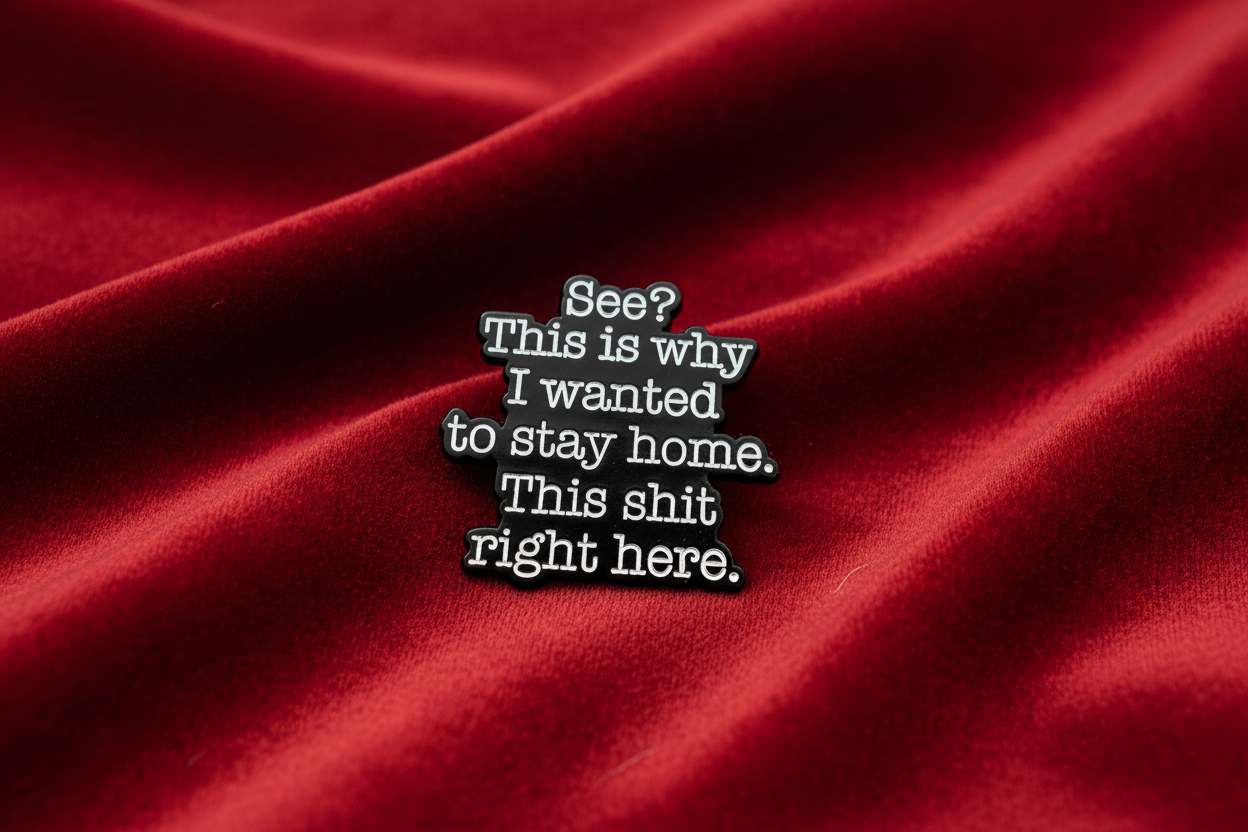 A black sarcastic pin with white text on a red fabric background