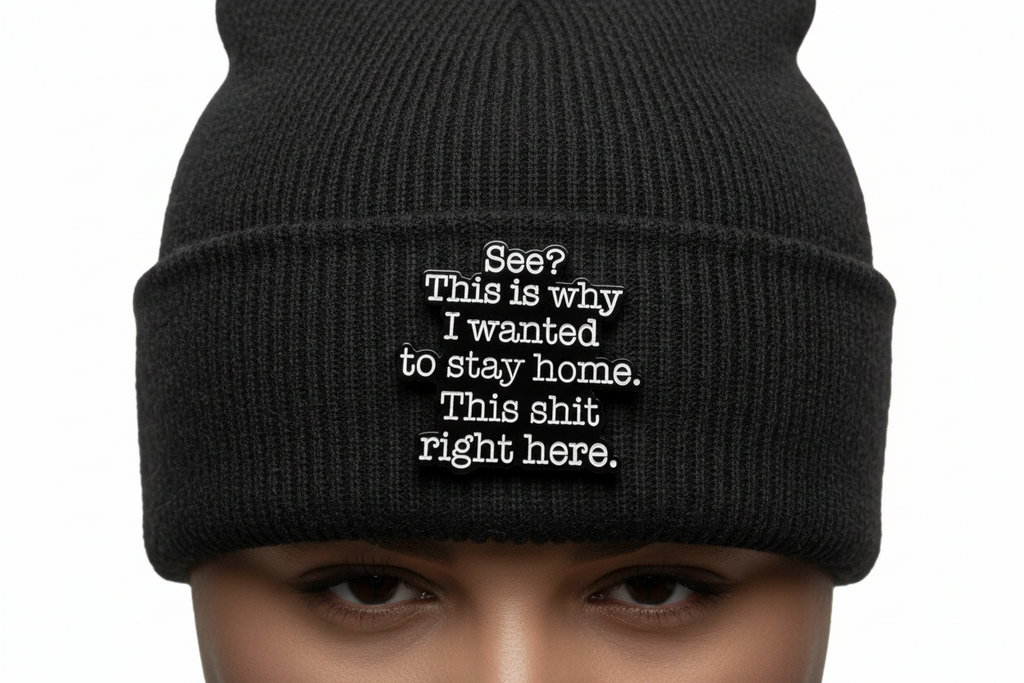 A black sarcastic pin with white text on a black beanie background