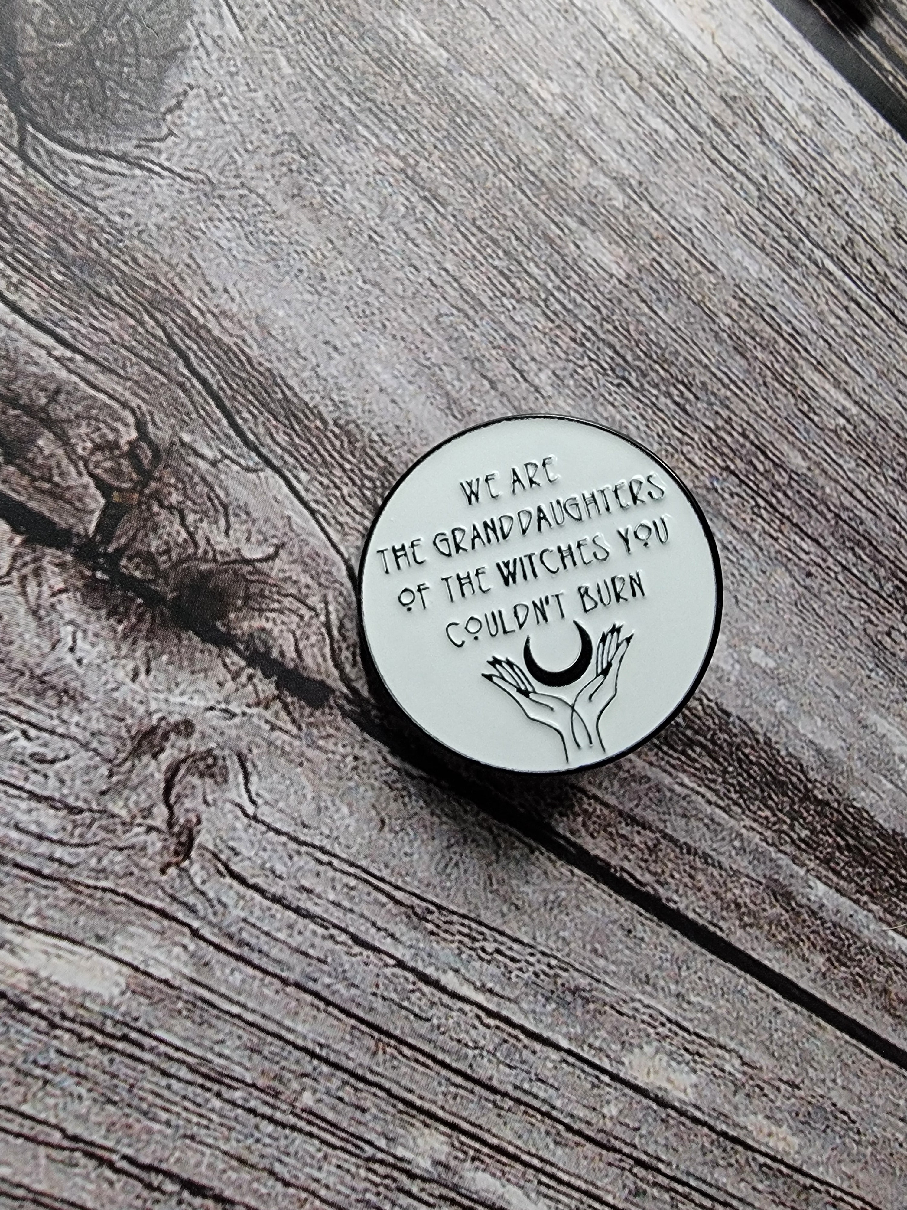 we are the granddaughters of the witches you couldn't burn enamel pin  on wood background spooky enamel pin with moon detail